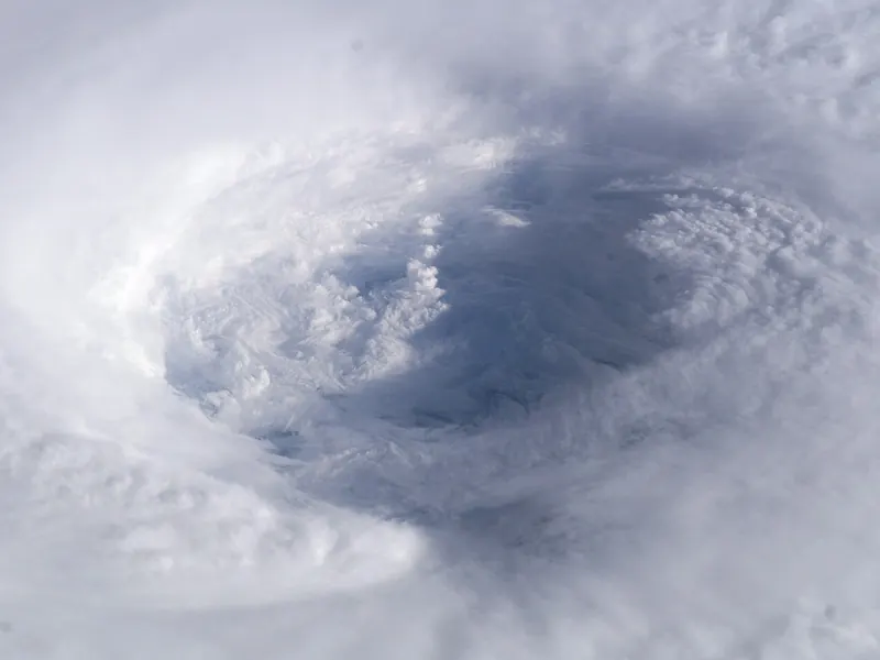 The round, cloud-free eye of a hurricane surrounded by a huge spiral of white cloud, seen from space
