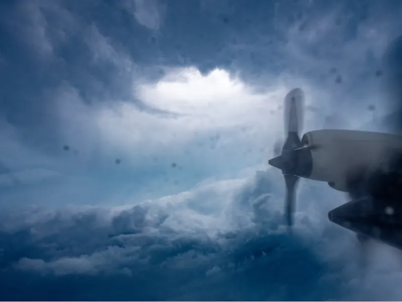 Looking out from an aircraft window into the eye of a hurricane, ringed by walls of cloud