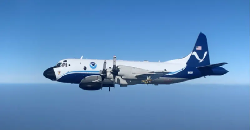 A four-propeller grey and white aircraft flying above the clouds