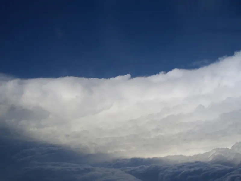 Looking up from inside the eye of a hurricane: a ring of tall cloud curves up and out like the walls of a stadium