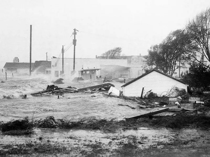 An old black-and-white photo of sea water flooding over a harbour road